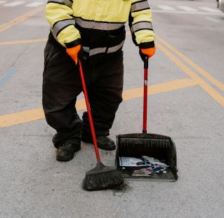 Street cleaner working in a busy city center, wearing bright safety gear.